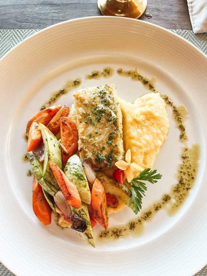 White fish fillet with herb sauce and roasted vegetables